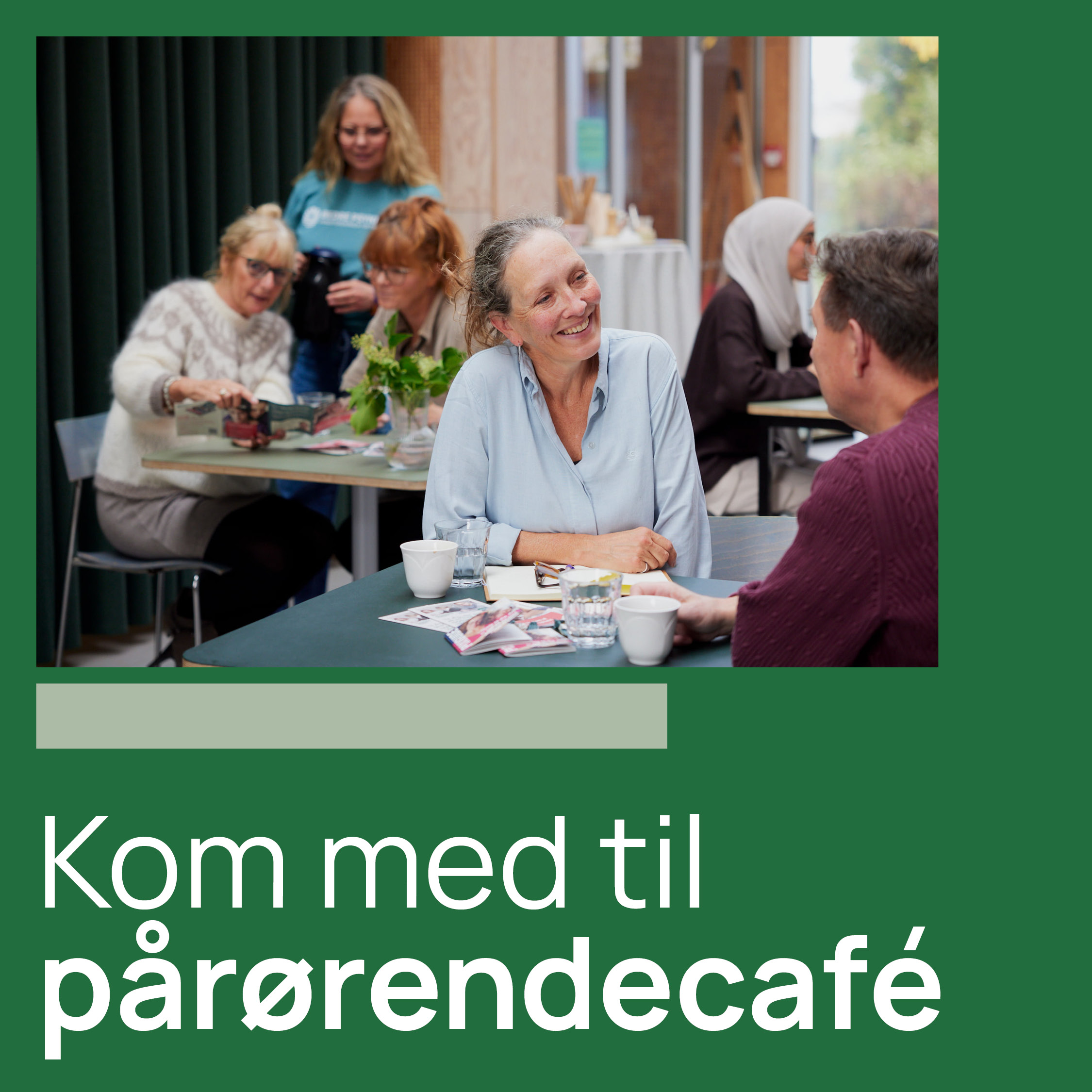 Flere voksne sidder og snakker ved borde med kaffe på en hyggelig café. Teksten siger: "Kom med til pårørendecafé".