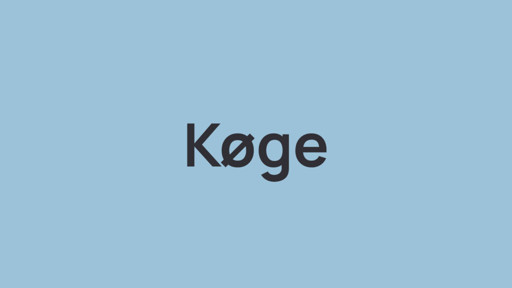 Sort tekst “Køge” på lyseblå baggrund.